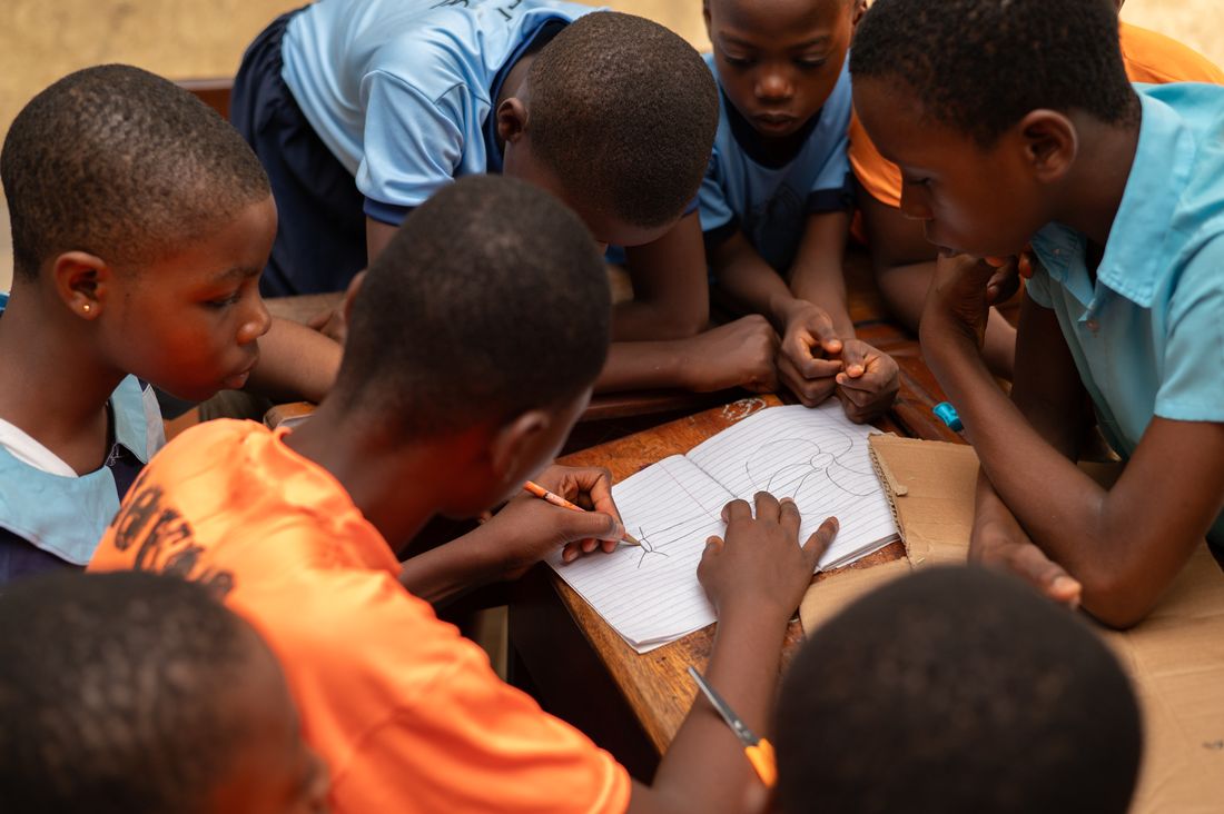 A group of pupils sketching a design together in an exercise book