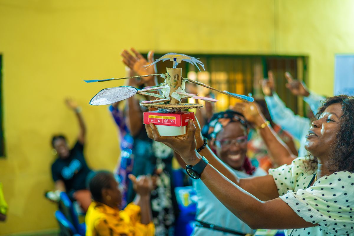 Teachers raising a flying machine they built from cardboard and paper during training